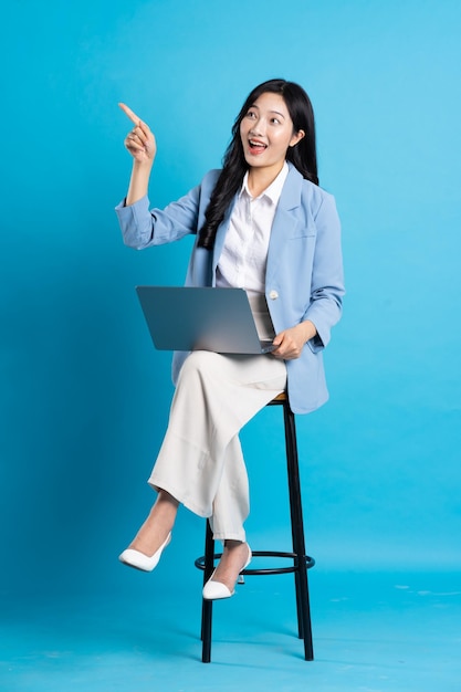 Portrait de femme d'affaires asiatique assis sur une chaise isolée sur fond bleu