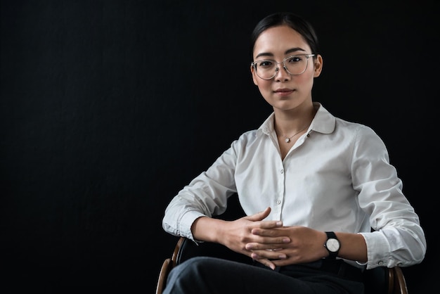 Portrait d'une femme d'affaires asiatique assise sur une chaise isolée sur fond noir