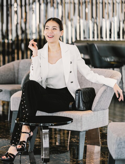 Portrait femme d'affaires asiatique portant un costume formel assis sur le canapé dans le hall moderne, un bureau ou un espace de coworking, les loisirs de la pause-café, la mode et le mode de vie après le temps de travail, le concept de gens d'affaires