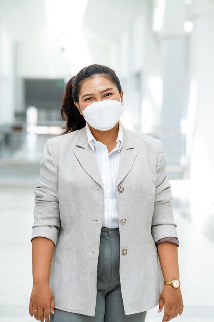 Photo portrait d'une femme d'affaires asiatique portant un masque chirurgical souriant à la caméra