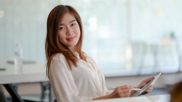 Portrait de femme d'affaires asiatique travaillant sur son projet et souriant à la caméra