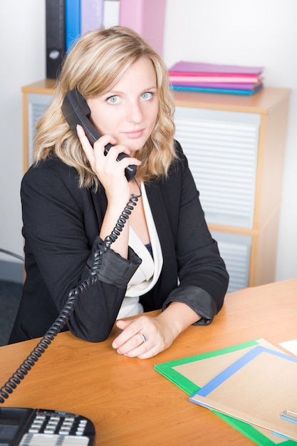 Portrait d'une femme d'affaires attrayante jeune à l'aide de téléphone au bureau