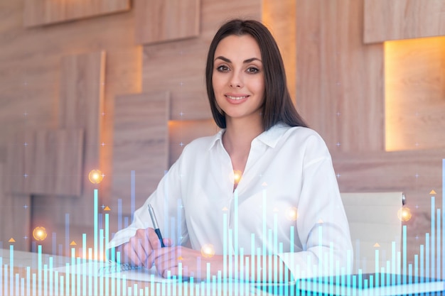 Portrait d'une femme d'affaires attrayante en tenue de soirée travaillant avec des documents et réfléchissant à la manière d'optimiser la stratégie de négociation au fonds de financement d'entreprise hologramme graphique Forex sur fond de bureau moderne