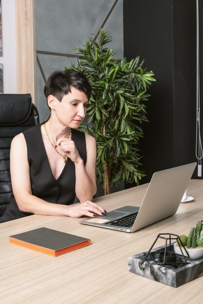 Portrait d'une femme d'affaires aux cheveux courts dans un bureau. Portrait commercial Une femme est assise devant l'écran d'un ordinateur portable.