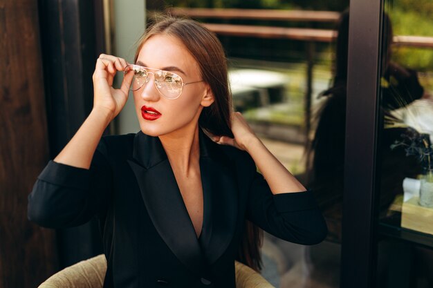 Portrait de femme d'affaires blonde touche ses lunettes et regarde de côté.- Image horizontale