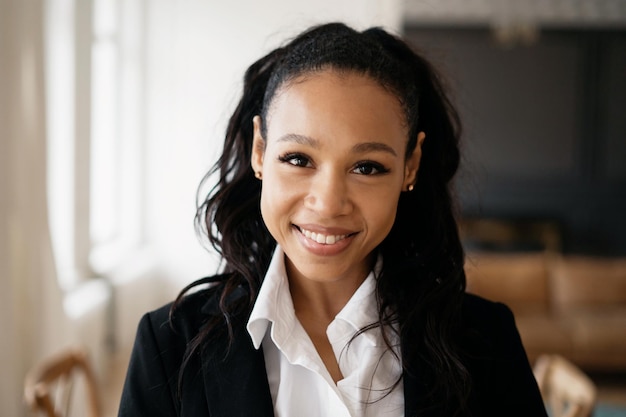 Portrait d'une femme d'affaires confiante souriante d'apparence afro assise dans un bureau en costume formel