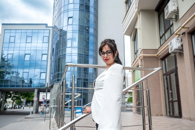 Portrait de femme d'affaires en costume debout près d'un immeuble de bureaux avec elle