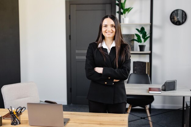 Portrait d'une femme d'affaires dans un bureau Une jolie jeune femme est debout dans le bureau près de son lieu de travail avec les bras croisés devant elle