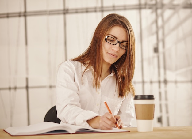 Portrait de femme d'affaires écrit un document à son bureau.