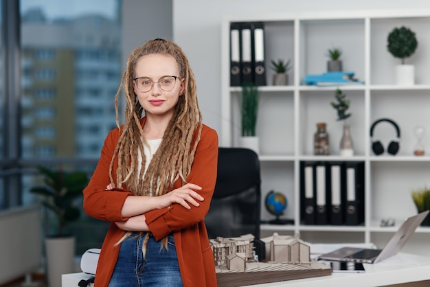 Portrait d'une femme d'affaires élégante avec des dreadlocks près de son lieu de travail avec maquette du futur bâtiment.