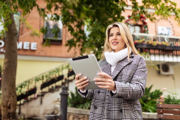 Portrait d'une femme d'affaires élégante avec une tablette dans ses mains sur le fond de l'urbain