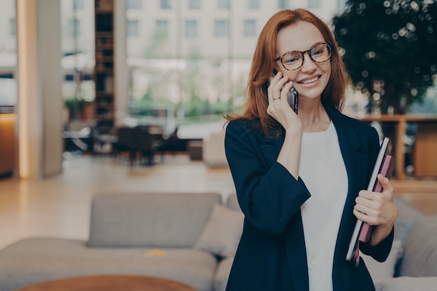 Portrait d'une femme d'affaires européenne positive séduisante ayant une conversation mobile