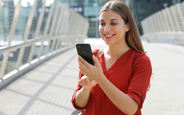 Portrait de femme d'affaires gaie à l'aide de l'application d'achat en ligne sur téléphone intelligent dans la rue de la ville