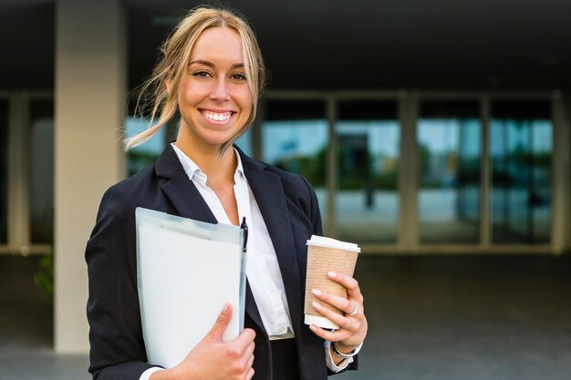 Portrait d'une femme d'affaires heureuse avec des documents et du café à emporter