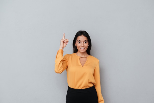 Portrait d'une femme d'affaires heureux souriant, pointant le doigt vers le haut