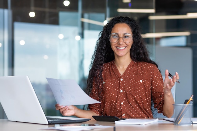 Portrait d'une femme d'affaires hispanique heureuse et réussie souriante et regardant la caméra tenant