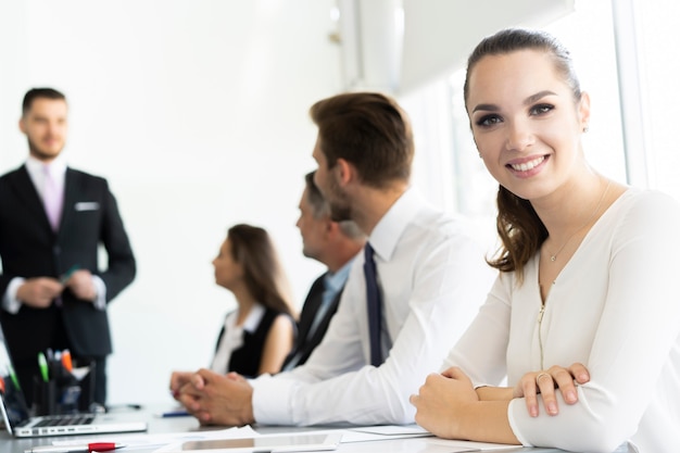 Portrait d'une femme d'affaires joyeuse assise à la table au bureau et regardant la caméra.