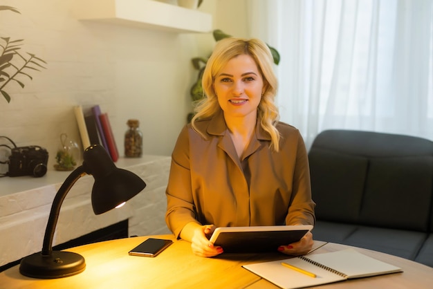 Portrait d'une femme d'affaires joyeuse assise à la table au bureau et regardant la caméra