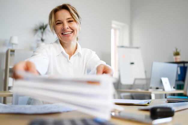 Portrait d'une femme d'affaires joyeuse donnant un document