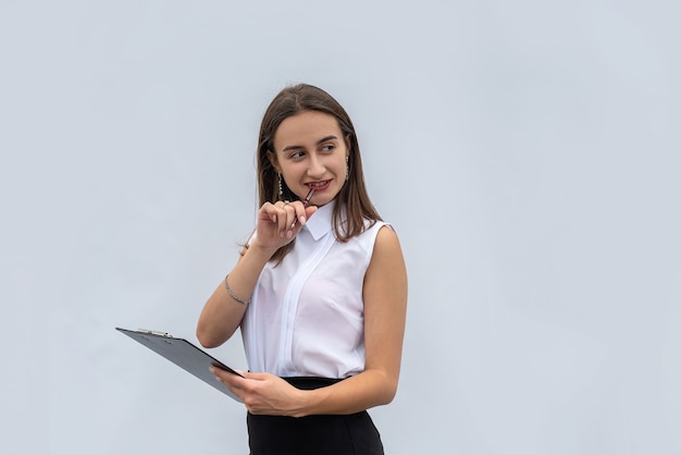 Portrait de femme d'affaires joyeuse avec presse-papiers, isolé sur un mur blanc