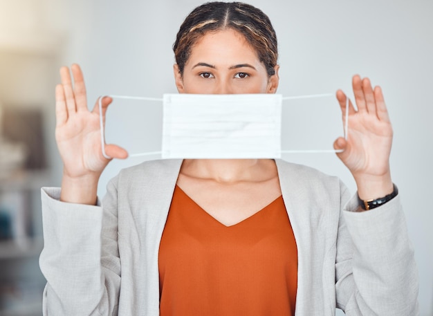 Portrait de femme d'affaires et masque à la fin du covid décollant la protection du visage sur fond flou Employée exempte de virus corona tenant et étirant des masques de fin ou d'arrêt de la pandémie