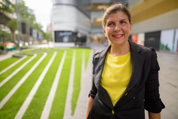 Portrait de femme d'affaires mature heureuse souriant à l'extérieur