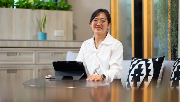 Photo portrait d'une femme d'affaires occupée à travailler sur une tablette numérique dans un espace de travail de bureau modéré une belle femme d'affaire asiatique attrayante travaillant dans un bureau à domicile