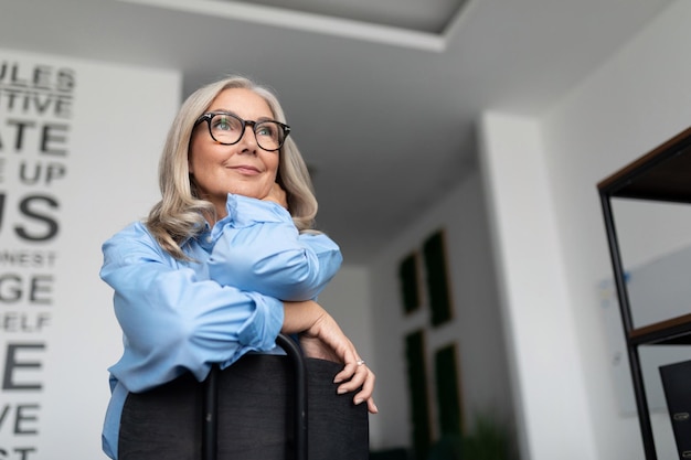 Portrait d'une femme d'affaires prospère assise sur une chaise à l'envers dans une entreprise de bureau moderne