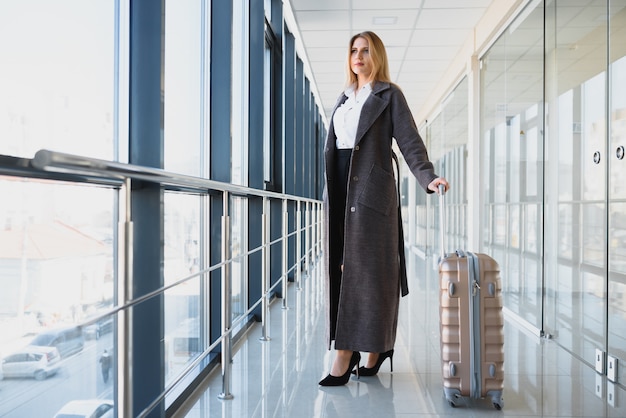 Portrait de femme d'affaires prospère voyageant avec cas à l'aéroport