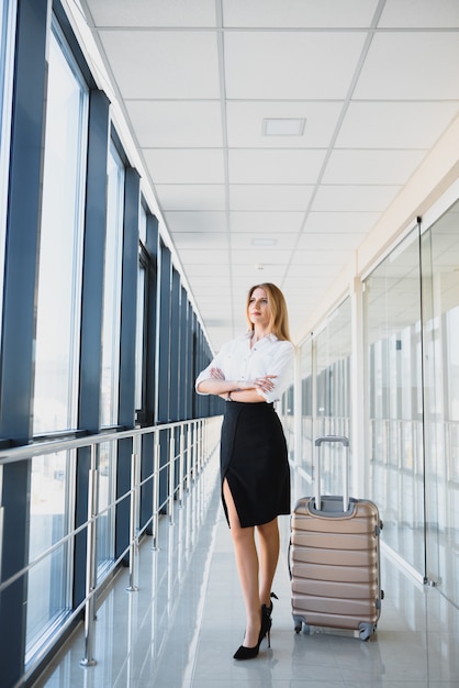 Portrait de femme d'affaires prospère voyageant avec cas à l'aéroport