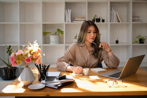 Portrait d'une femme d'affaires réfléchie travaillant avec un ordinateur portable au bureau