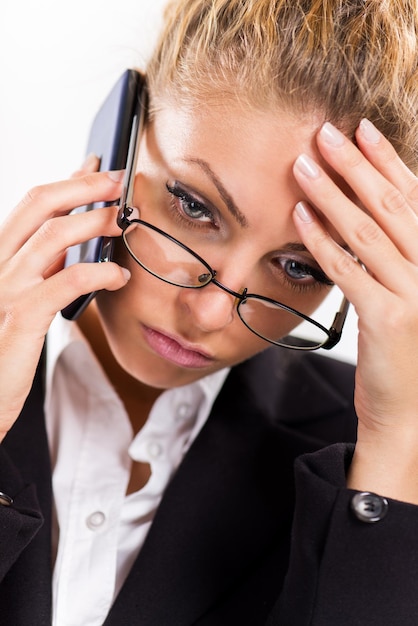 Portrait d'une femme d'affaires séduisante avec des lunettes à l'aide d'un téléphone portable. Elle pense.