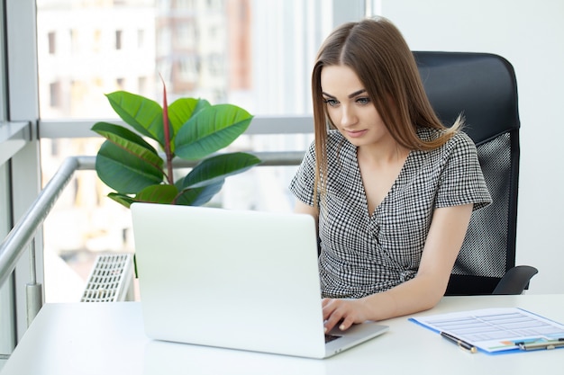 Portrait d'une femme d'affaires sérieuse utilisant un ordinateur portable au bureau.