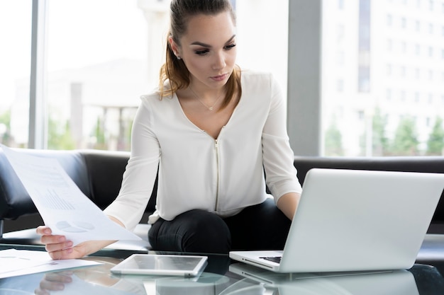 Portrait d'une femme d'affaires sérieuse utilisant un ordinateur portable au bureau.