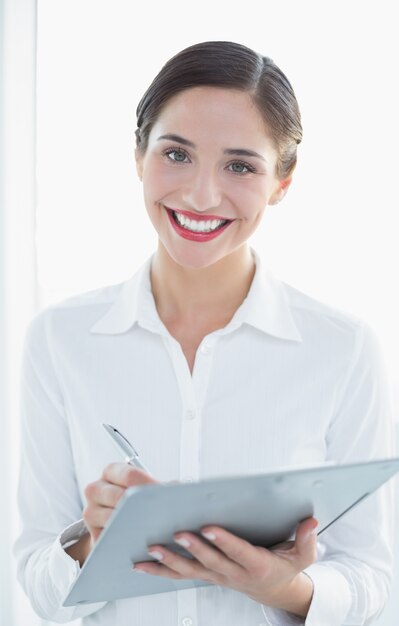 Portrait d&#39;une femme d&#39;affaires souriant avec le presse-papier et un stylo