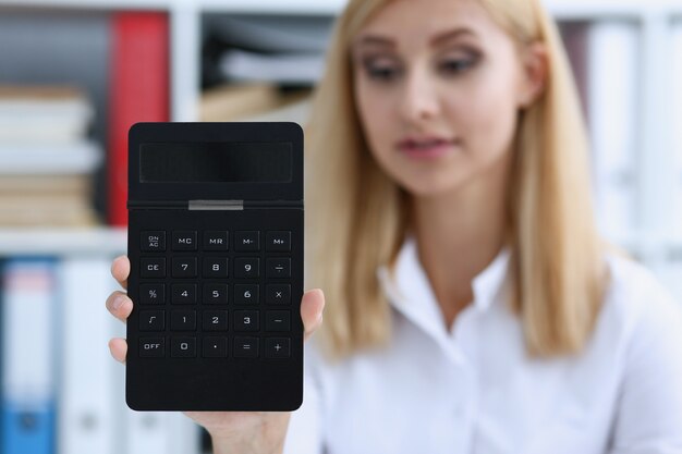 Portrait de femme d'affaires souriant tient la calculatrice à la main