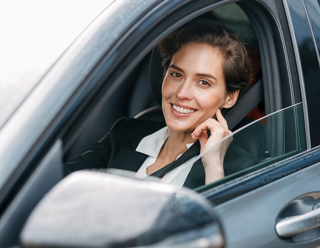 Portrait d'une femme d'affaires souriante assise dans une voiture
