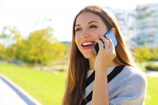 Portrait de femme d'affaires souriante ayant une conversation sur son téléphone portable à l'extérieur.