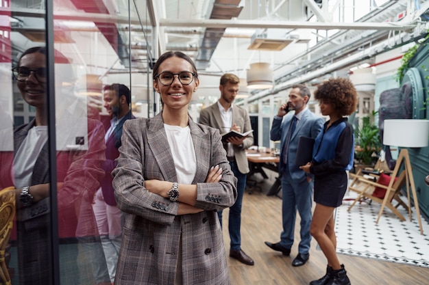 Portrait d'une femme d'affaires souriante debout dans un bureau moderne sur fond de collègues