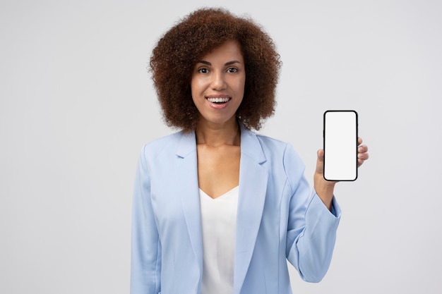 Portrait d'une femme d'affaires souriante positive montrant un smartphone avec écran vide