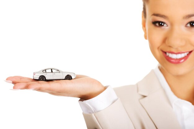 Photo portrait d'une femme d'affaires souriante tenant une voiture jouet sur un fond blanc