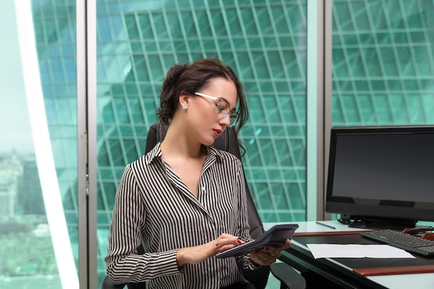 Portrait de femme d'affaires en tapant sur la calculatrice