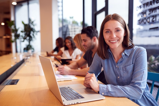 Portrait de femme d'affaires travaillant au bureau dans un espace de travail de bureau à aire ouverte partagé