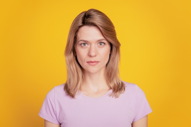 Portrait d'une femme d'affaires de travailleur calme regarde le visage calme de la caméra sur fond jaune