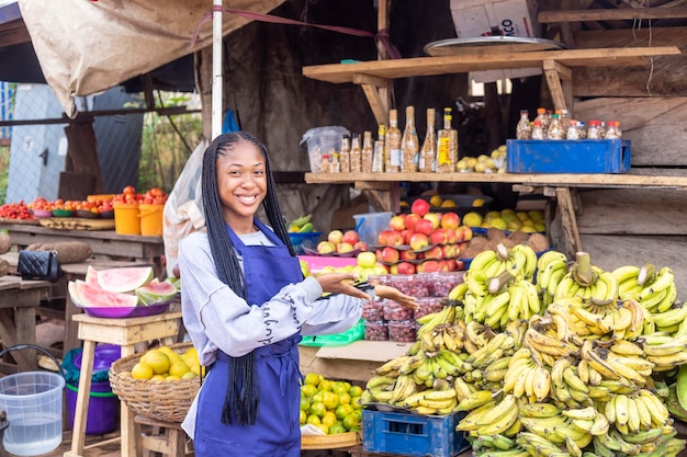 Portrait d'une femme africaine du marché souriant montrant ses marchandises