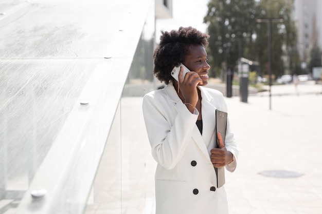 portrait d'une femme africaine élégante et prospère avec un téléphone portable