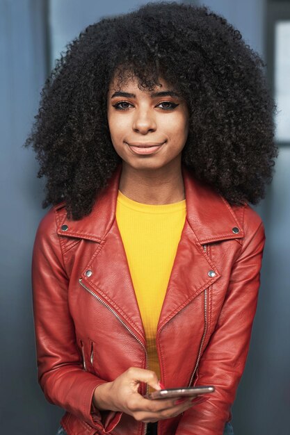 Portrait d'une femme afro-américaine aux cheveux bouclés assise à l'extérieur et regardant la caméra