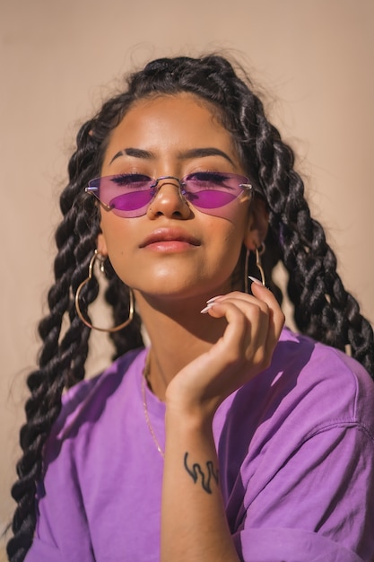 Portrait d'une femme afro-américaine aux cheveux longs portant une chemise violette et des lunettes de soleil