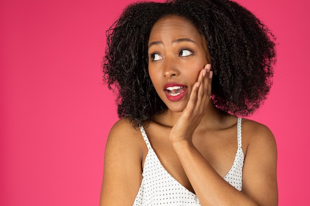 Portrait d'une femme afro-américaine curly millénaire heureuse et pensive surprise regardant l'espace vide