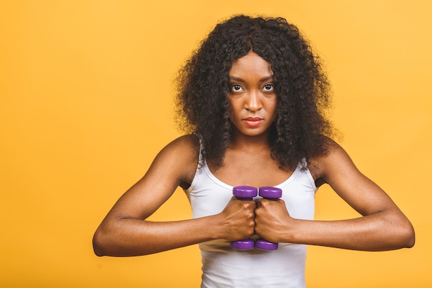 Portrait de femme afro-américaine exerçant son muscle avec des haltères